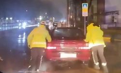 Arızalanan otomobili trafik polisleri yağmurun altında itti