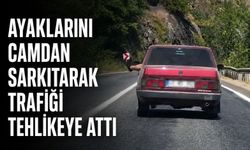 Ayaklarını camdan sarkıtarak trafiği tehlikeye attı
